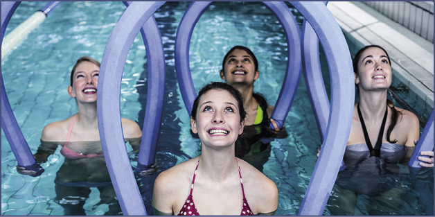 Happy fitness class doing aqua aerobics with foam rollers in the pool