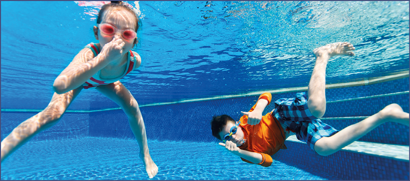 Kids having fun playing underwater in swimming pool on summer vacation
