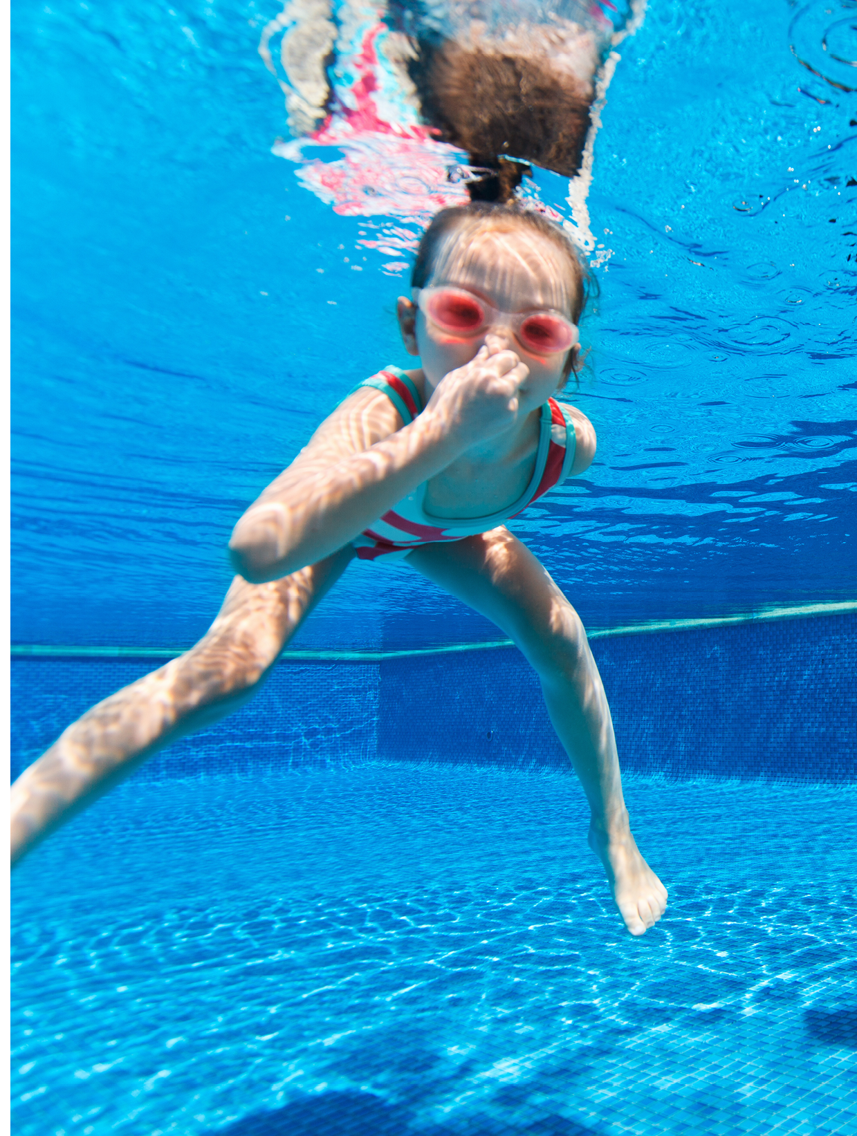 Kids having fun playing underwater in swimming pool on summer vacation