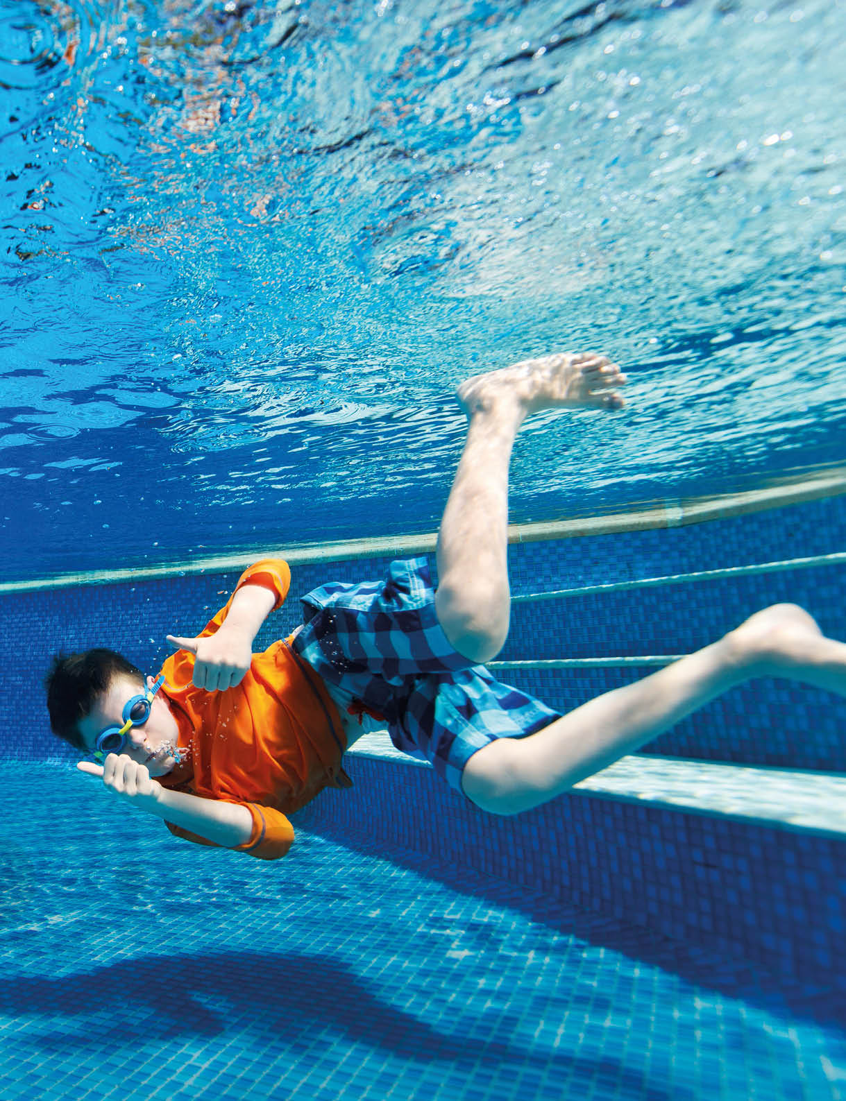 Kids having fun playing underwater in swimming pool on summer vacation