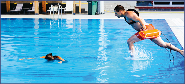 Lifeguard rescue training - young man jumping into a swimming pool to rescue drowning victim