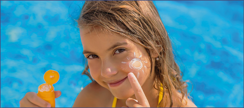 The child is putting sunscreen on her face. Selective focus. Kid.